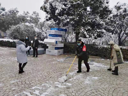 郑州巡防队员协同公园工作人员清理广场上的积雪