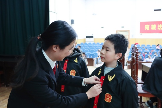 法官助理朱丰秋为参加模拟法庭的学生整理小法袍
